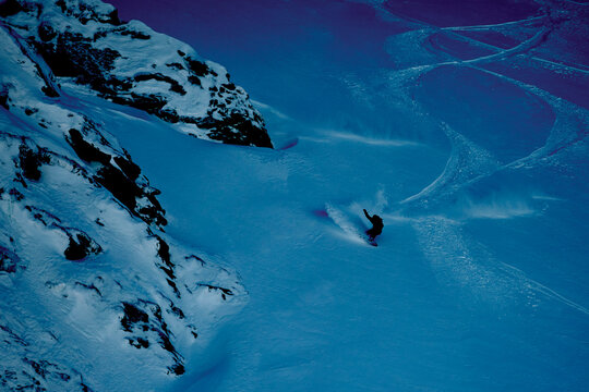 Snowboarder Rides Down a Mountain Slope