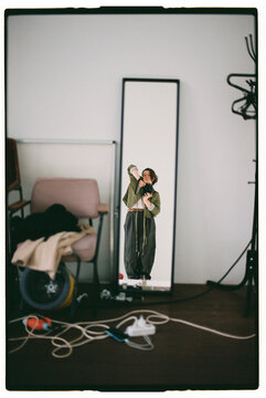 Girl takes self-portraits in the mirror in a simple room setting