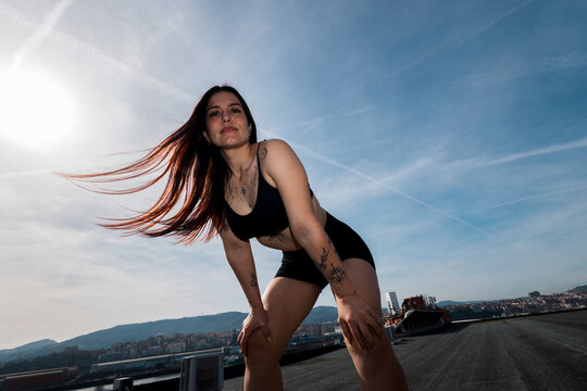 Woman in a semi-squat pose on a sunlit rooftop