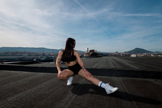 Sporty woman exercising on a rooftop in bright sunlight