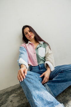 Woman leaning against a wall, relaxed and serene in casual clothes.