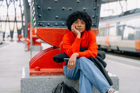 A woman sitting on the platform of the train station