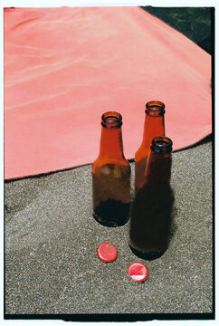 Three Empty Beer Bottles on Warm Sandy Beach