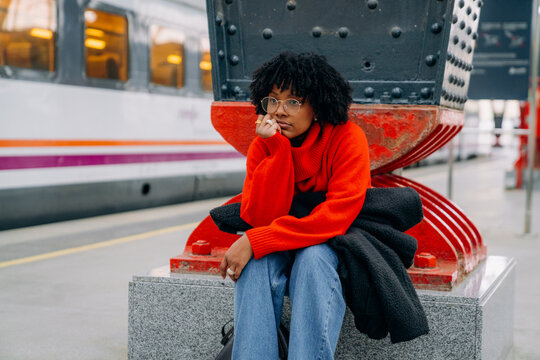 A woman sitting on the platform of the train station