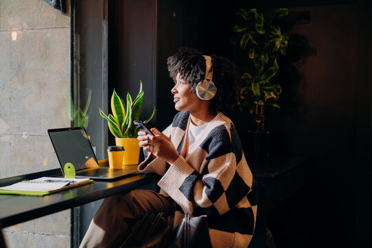 A woman using a mobile phone and laptop in a cafe
