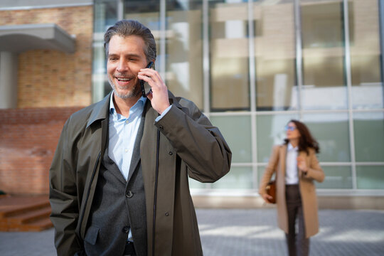 Man talking on phone while woman walks by