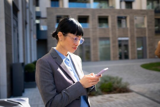 Woman in a suit checks phone outside