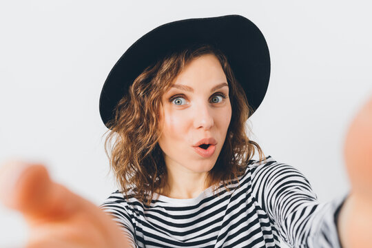 Woman in black hat and striped top, surprised look, pointing forward