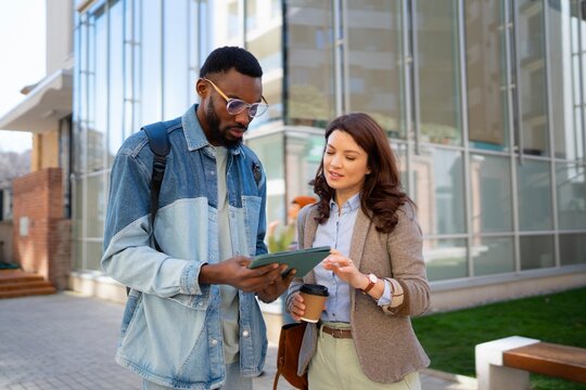 Two people are standing outside a modern building