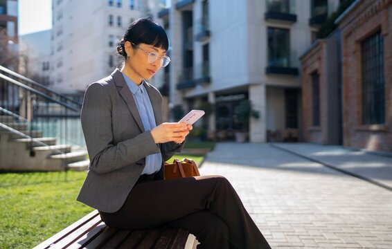 Woman using a phone while sitting in a city park