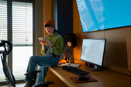 Young person using phone in a modern workspace
