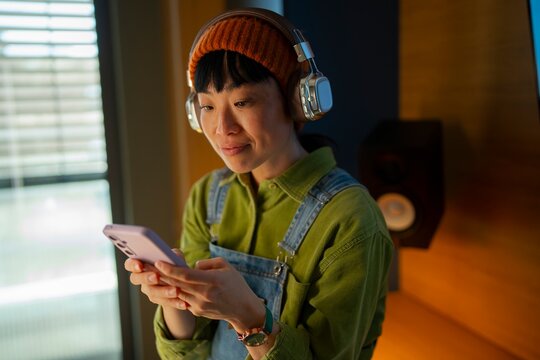 Woman with headphones using smartphone at home