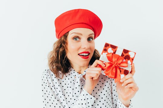 Smiling woman with curly hair presents a wrapped gift box