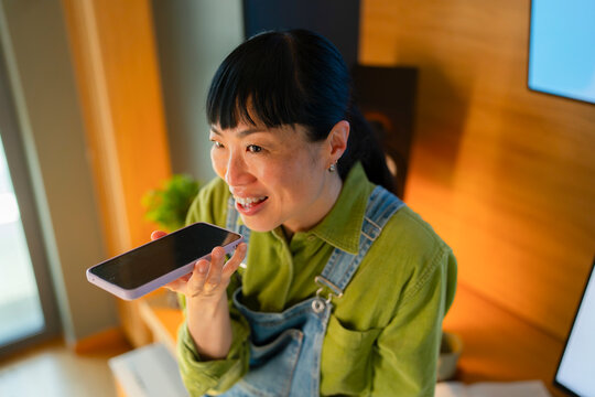 Woman speaks into smartphone in a modern workspace