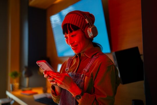 Person wearing headphones checks phone in room