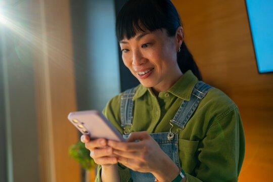 Smiling woman using smartphone indoors