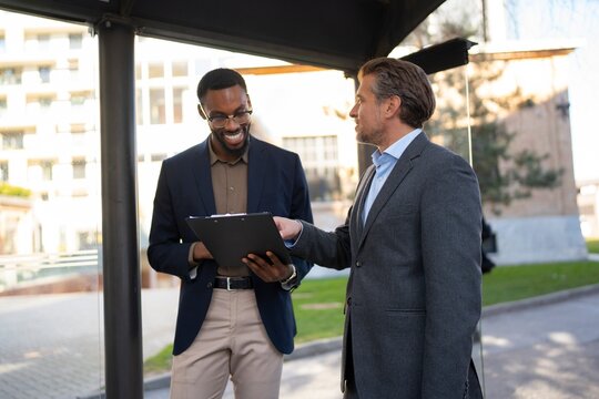 Reviewing documents together outdoors near office