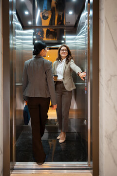 Women in suits share a moment in an elevator