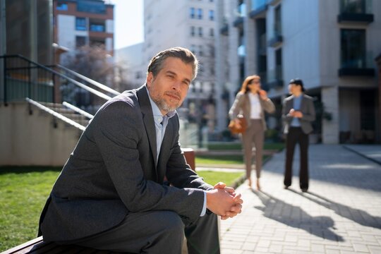 Man sitting on stairs while two people talk nearby