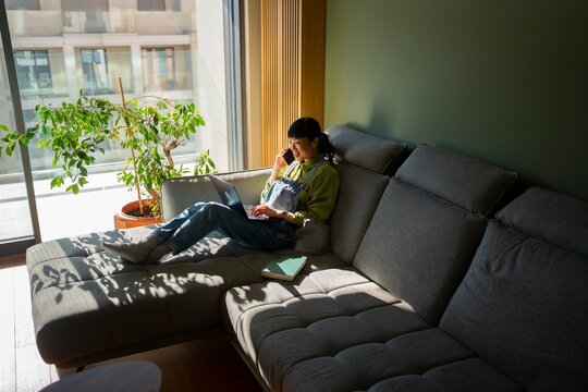 Woman working from sofa in natural sunlight