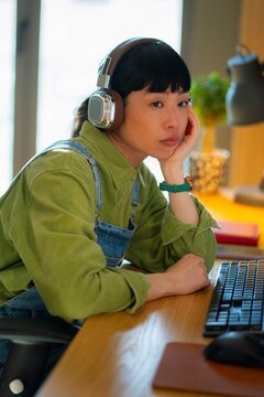 A young woman sits at a desk with a computer