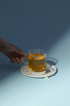 A glass of warm tea is held over a white plate, a relaxing scene
