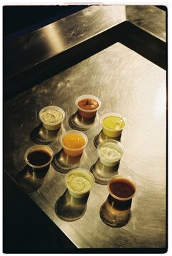 Table with small takeout containers of BBQ, mayo, ketchup, mustard
