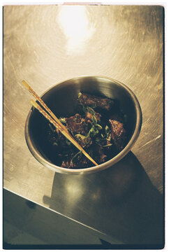 Top view of Asian BBQ ribs served in a stainless steel bowl with chops