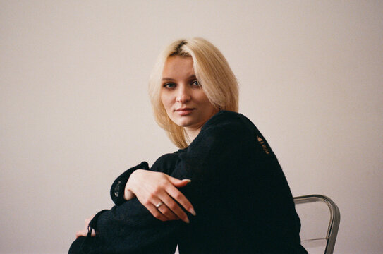 Young Woman in Black Sweater on Chair, Arms Crossed, Film