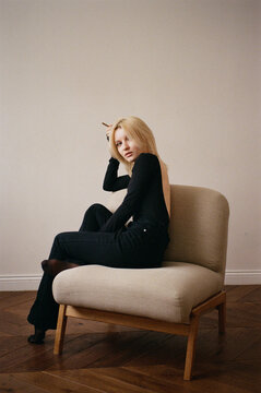 Young Woman in Backless Black Outfit on Armchair, Film Portrait