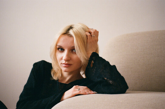 Young Woman in Black Lace Top on Sofa, Hand in Hair 