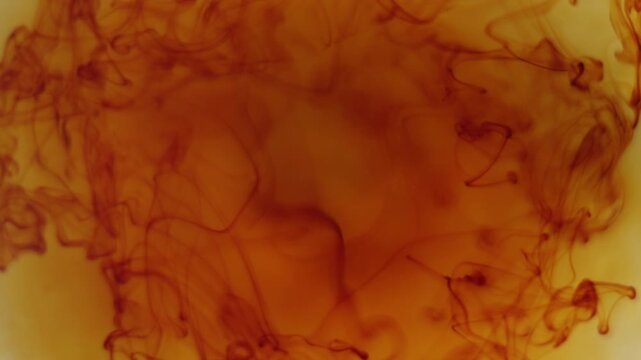 Abstract fluid composition with iodine dissolving in water, forming delicate swirling shapes and smooth color transitions.