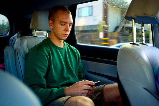 Man uses his phone in the back of a car