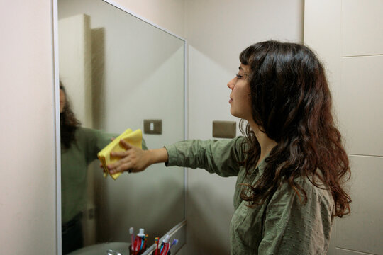 Woman Wiping Bathroom Mirror