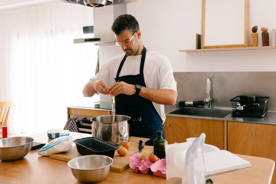 Man wearing an apron baking a cake in a modern kitchen