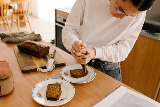 Woman decorating slices of freshly baked cake with a pastry bag