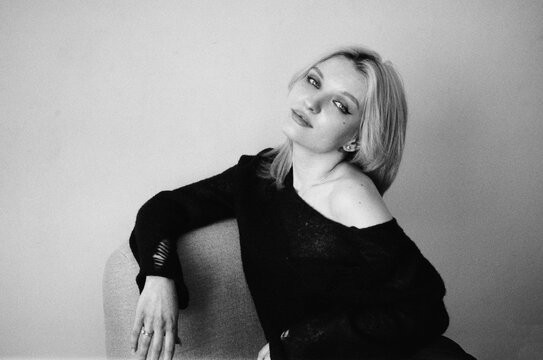 TITLE:
Blonde on Armchair in Off-Shoulder Black Top, B&W Portrait