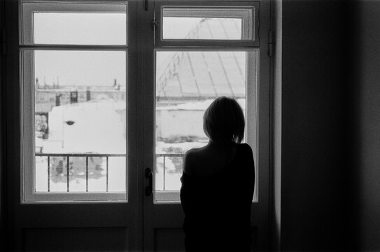 Silhouette of Blonde Looking Out at Snowy Rooftops, B&W 
