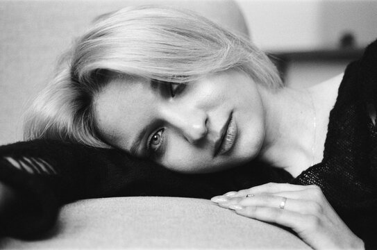 Pensive Blonde Woman Resting on Sofa in B&W Portrait