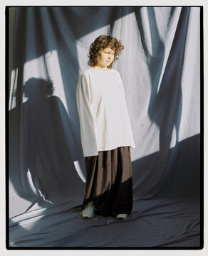 Light falling on a woman wearing white shirt and black pants indoors