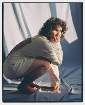 Woman squatting in a simple setting with soft lighting