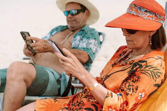 mature Couple Using Smartphones While Relaxing on Beach Chairs
