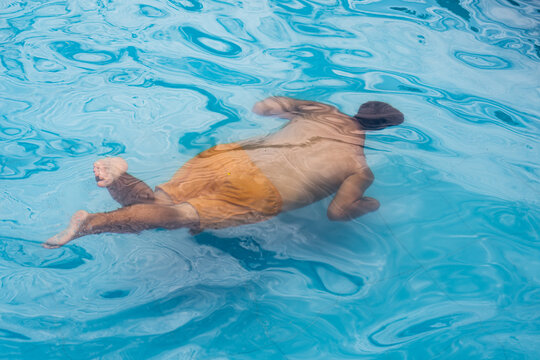 Man Swimming Underwater in Blue Pool on Sunny Day