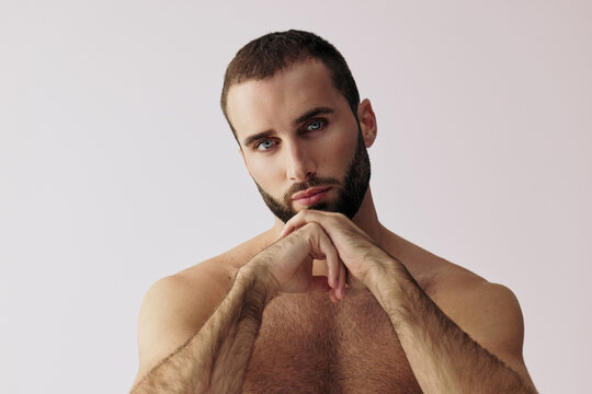 Man Poses With Hands Under Chin in a Studio Setting