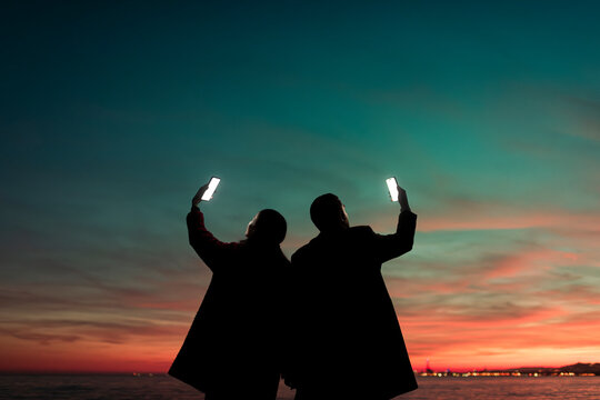 Couple Raising Phones to the Sky Together