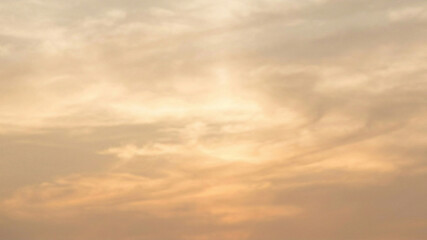 Obraz premium Warm sunset sky with scattered clouds at dusk, transitioning to golden hues and soft light.