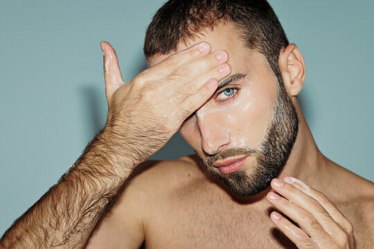 Man Applying Skincare on His Face in a Light Blue Background