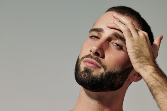 Man Touches His Forehead and Gazes at the Camera Indoors