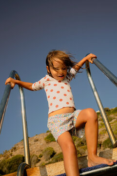 Little girl coming down the ladder, deck by the Mediterranean Sea