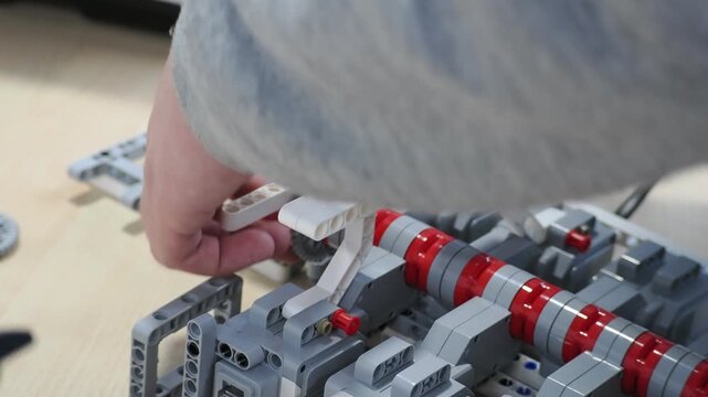 young boy constructor scientist assemble the wheeled machine robot in the lab. boy teenager collects according to instructions robot constructor. connects wires, programs. develops intelligence